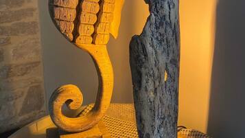 A wooden seahorse sculpture on a textured surface, next to a piece of driftwood.