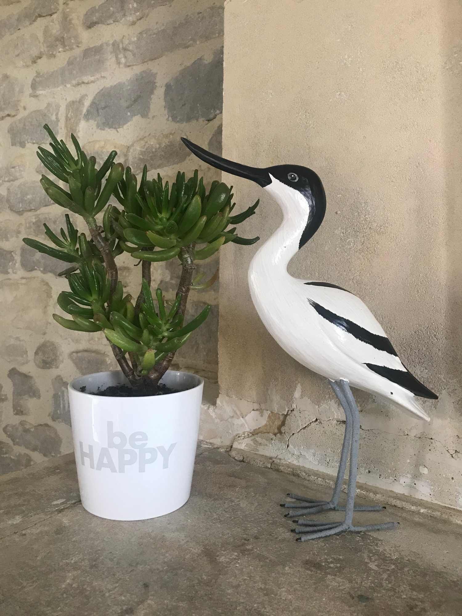 Eine Blumentopf-Pflanze mit einer Vogel-Figur daneben.