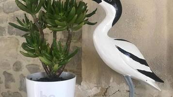 Eine Blumentopf-Pflanze mit einer Vogel-Figur daneben.