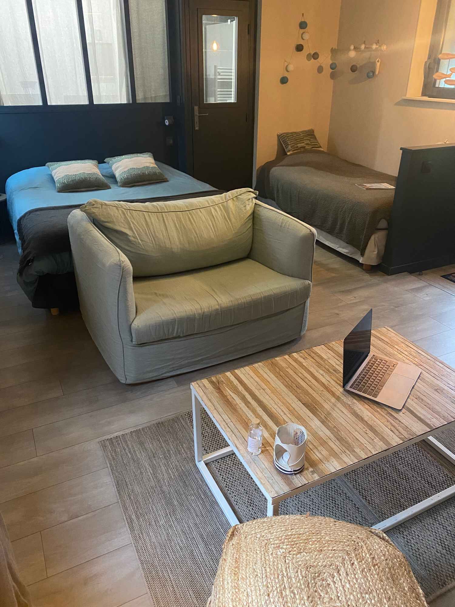 Una habitación moderna con sofá, cama, una mesita con un ordenador portátil y una puerta que da a una vista.