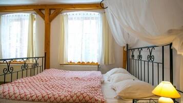 A bedroom with a bed, a window with curtains, a radiator, and a lamp on a bedside table.