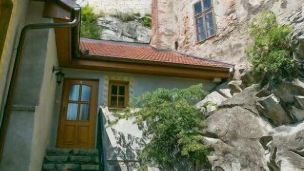 Un edificio de piedra con una puerta de madera y una escalera que conduce a un pequeño porche.