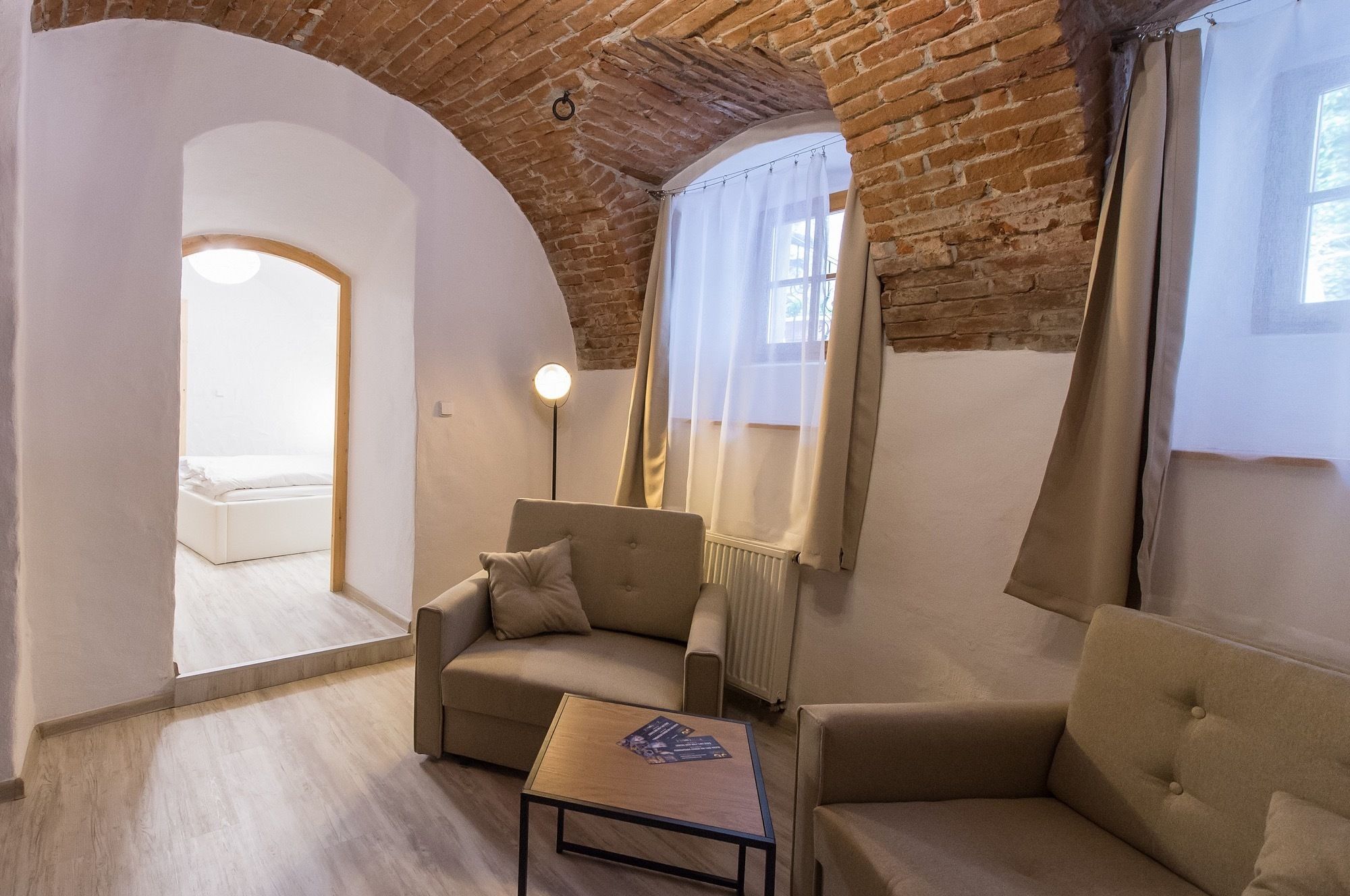 A cozy room with a brick ceiling, a sofa, a small table, and a radiator.