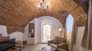 Una sala de estar acogedora con techo de ladrillo, un televisor de pantalla plana, un sofá y una mesa de centro.