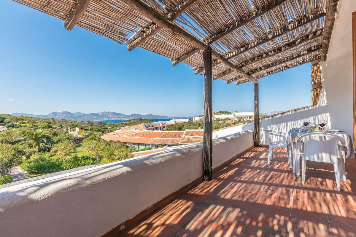 Ein Balkon mit Blick auf ein Stadion und Grünflächen, ausgestattet mit einem Tisch und Stühlen.