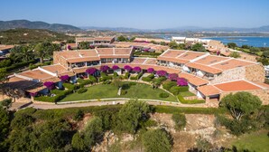 A coastal resort with terracotta-roofed buildings, lush gardens, and a view of the sea. - Capo Ceraso Family Residence (Olbia)