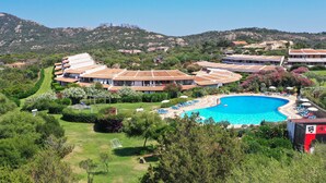 A resort with a large swimming pool, multiple guest rooms, and a mountainous backdrop. - Capo Ceraso Family Residence (Olbia)