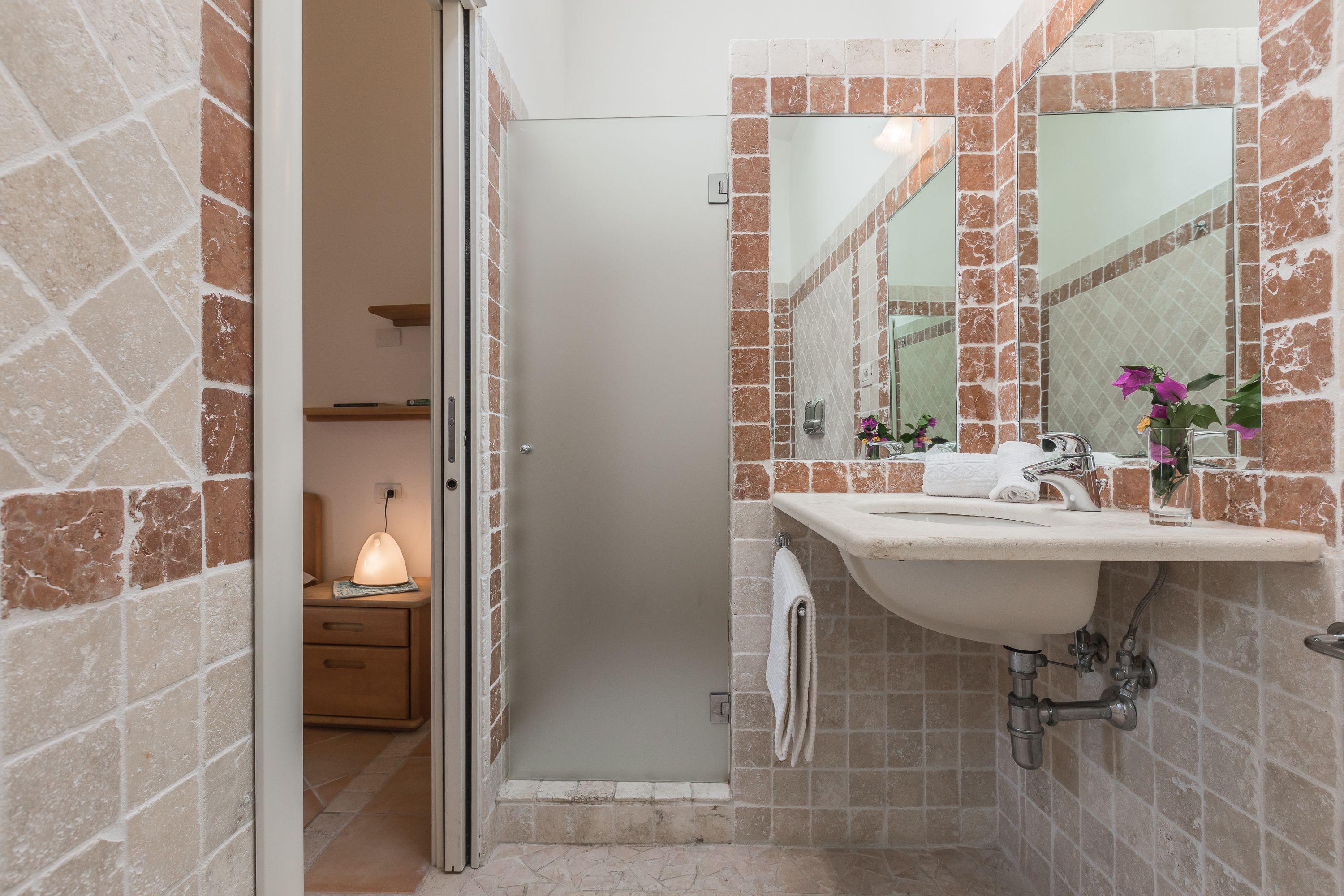 A bathroom with a sink, mirror, and shower area.