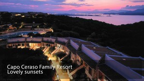 Ein Resort mit traditioneller Architektur und Meerblick bei Sonnenuntergang.