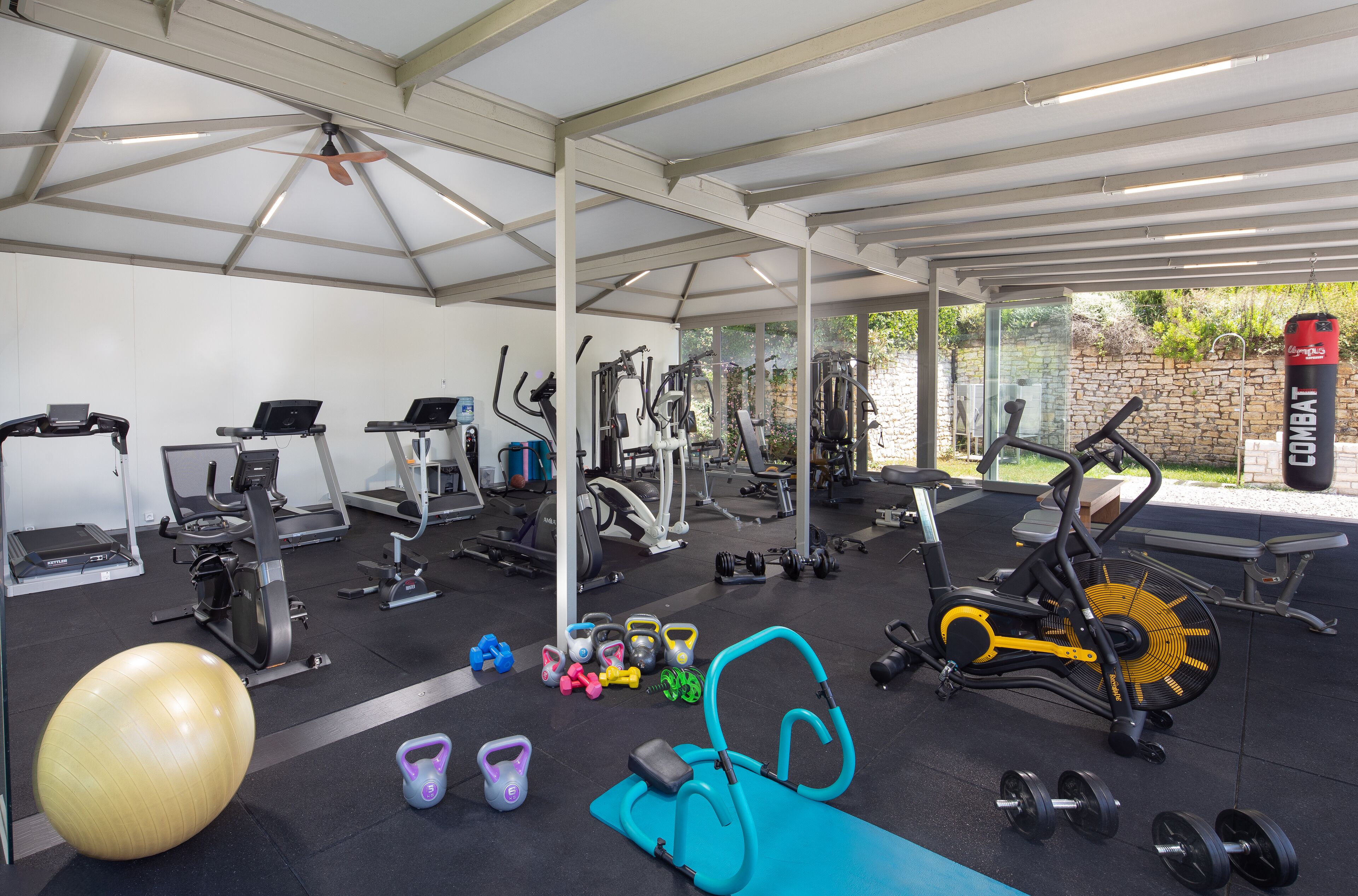 Ett gym med olika typer av träningsutrustning, inklusive löpband, motionscyklar och fria vikter.