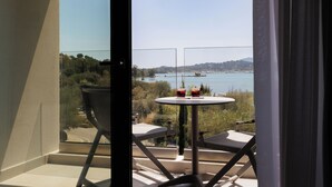 Varanda com mesa e cadeiras, vista para um corpo d'água e vegetação.