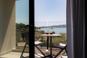 A balcony with a table and chairs, overlooking a body of water and greenery.