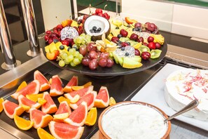 A fruit platter with various fruits and a cake with white frosting. - Rodostamo Hotel & Spa - Adults friendly (Corfu)