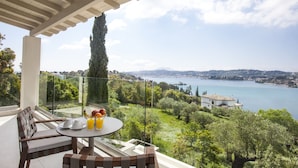 Varanda com mesa posta para o café da manhã, com vista para um lago cênico e vegetação ao redor.
