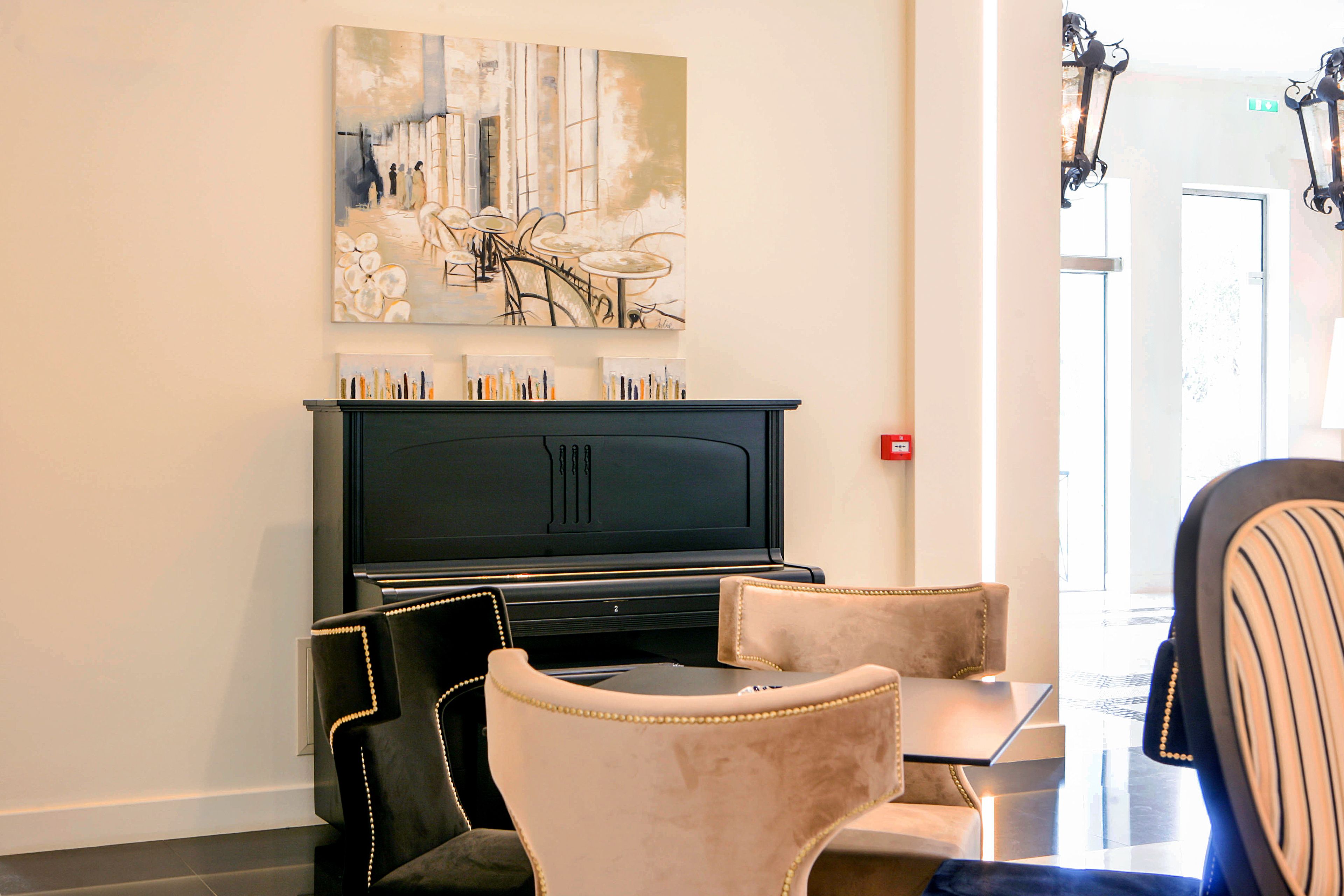 A lobby with a black piano, beige chairs, and a large abstract painting on the wall.