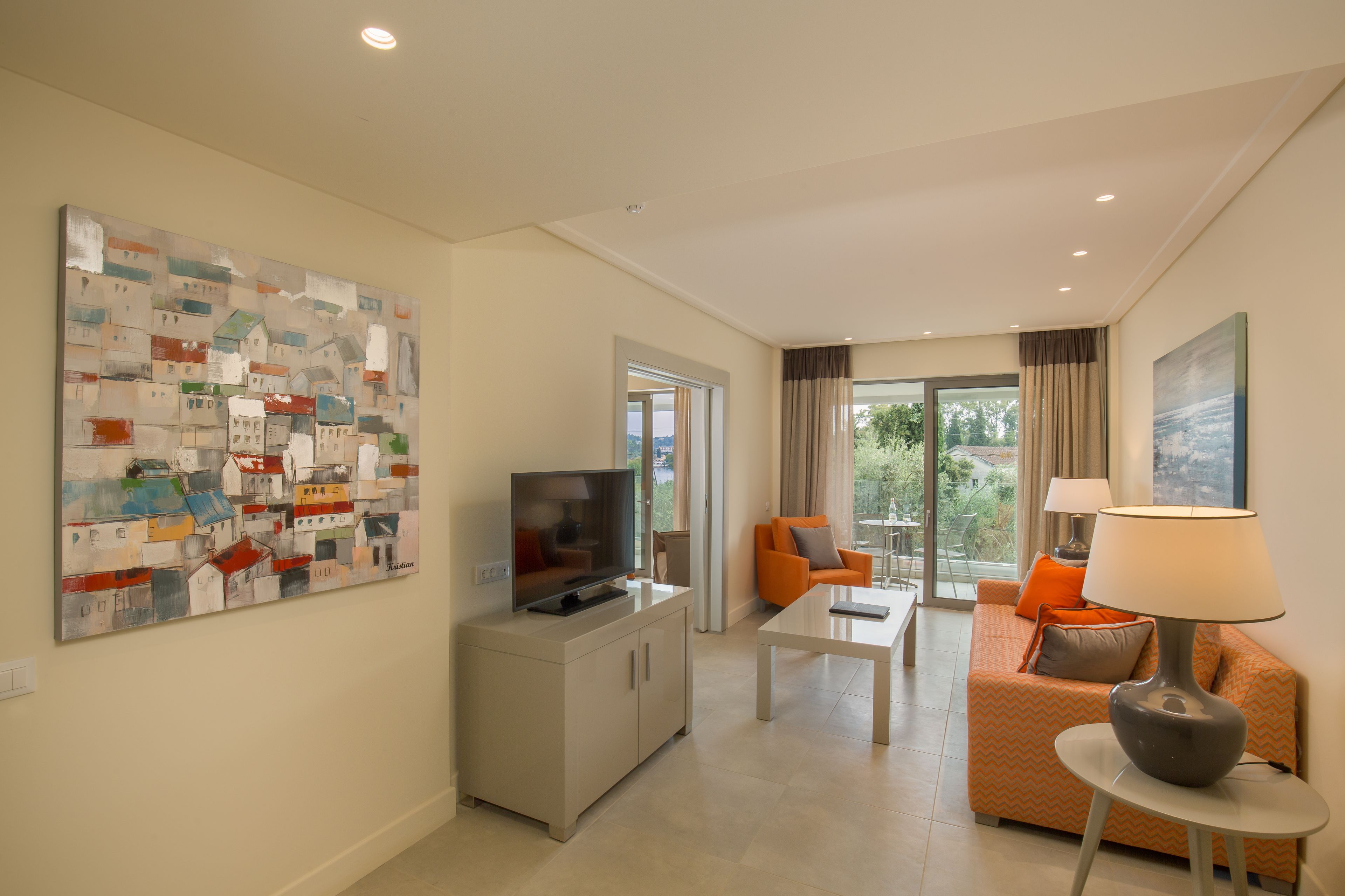 A modern living room with a flat-screen TV, a coffee table, an orange sofa, and a lamp.
