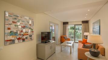A modern living room with a flat-screen TV, a coffee table, an orange sofa, and a lamp.