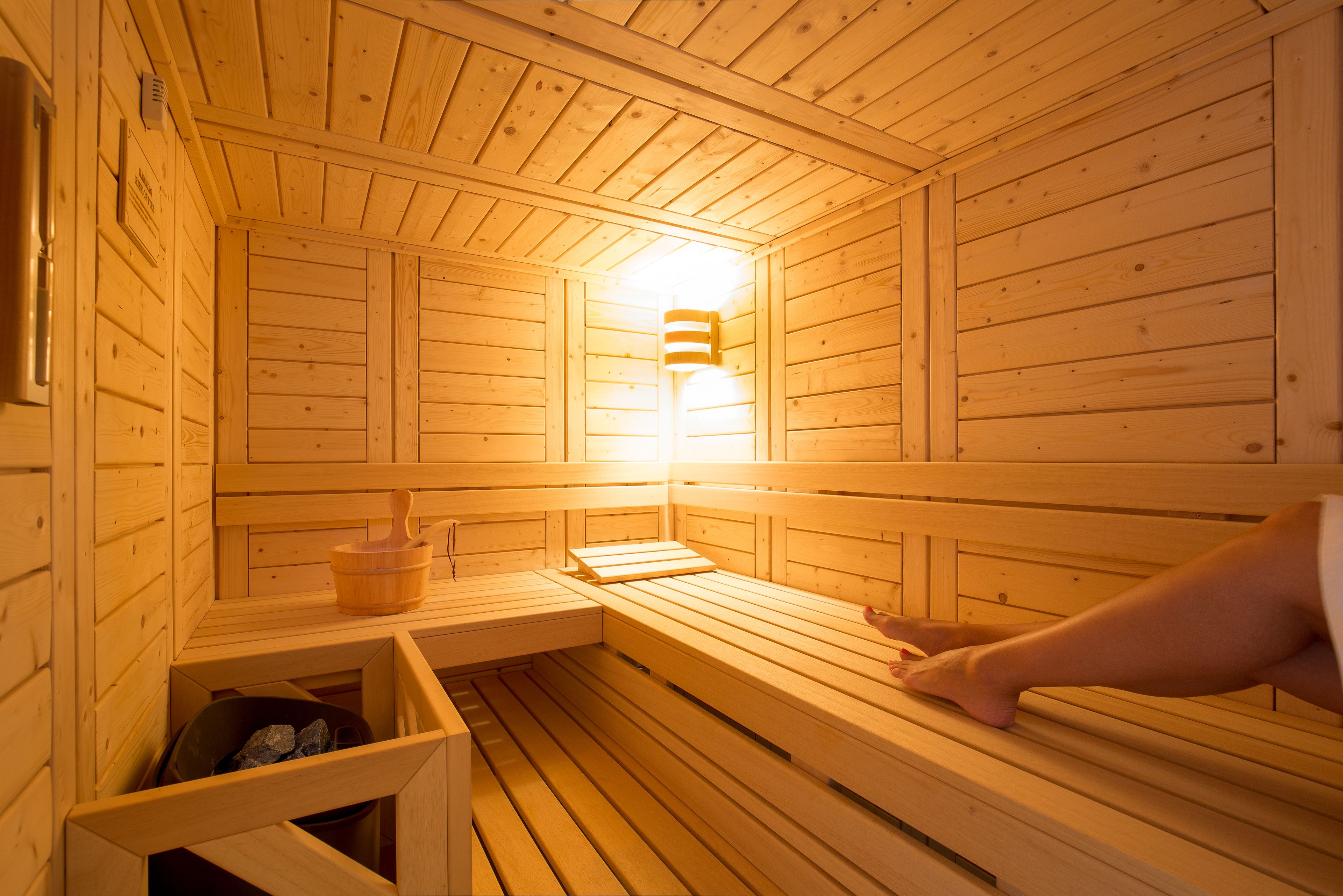 A wooden sauna with benches and a wall-mounted heater.