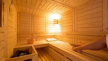 A wooden sauna with benches and a wall-mounted heater.