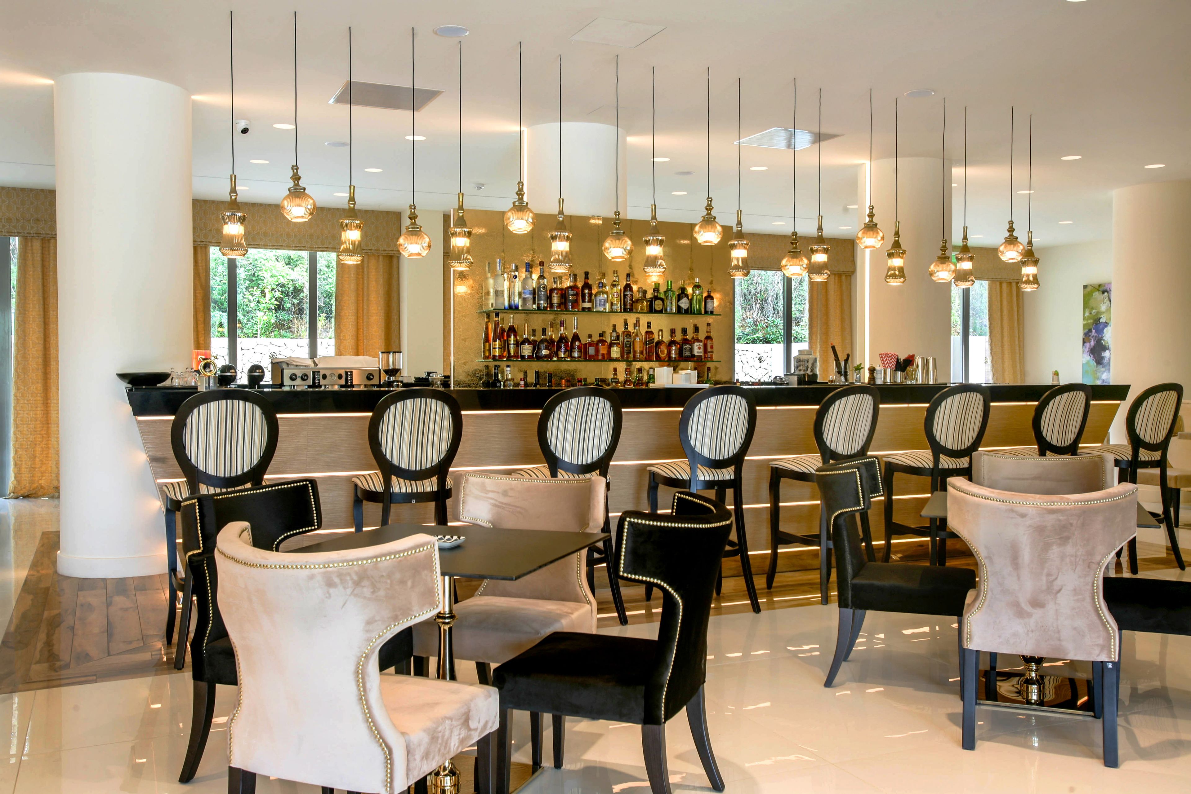 Un restaurant doté d’un bar, de nombreuses tables et chaises, et de luminaires suspendus.