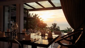 Un comedor con una mesa dispuesta para cuatro personas, con vistas a una puesta de sol.