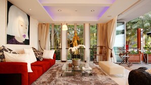 Una sala de estar moderna con un sofá rojo, una mesa de centro de vidrio y un ventanal con cortinas.