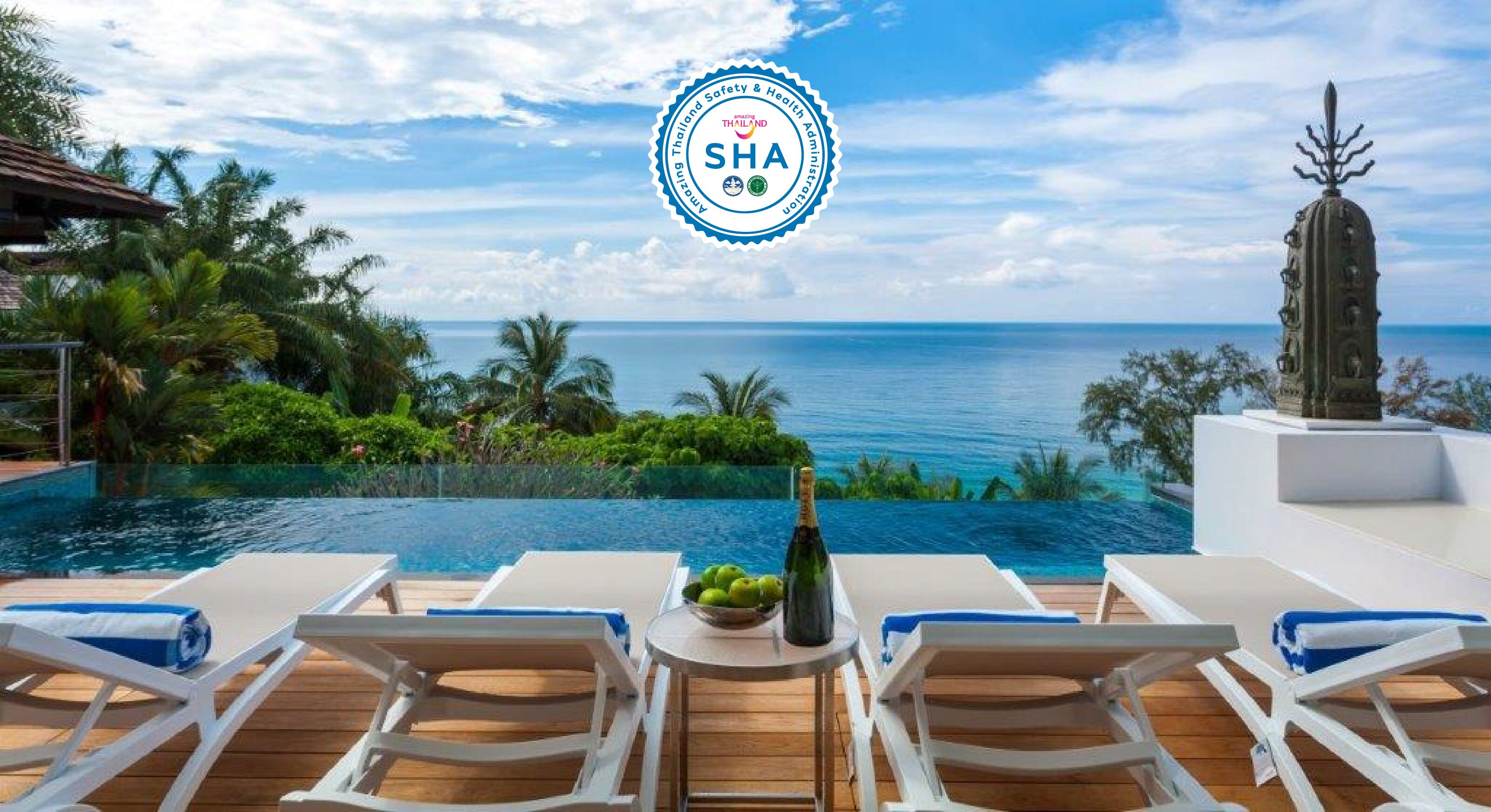 A poolside area with lounge chairs, a bottle of champagne, and a view of the ocean.