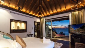 Un dormitorio con una cama grande, televisión y balcón con vista al océano.