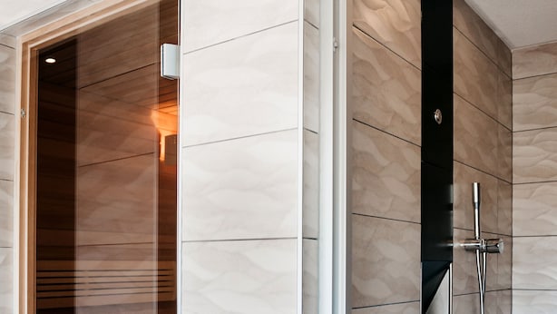 A modern bathroom with a wooden sauna, a glass shower enclosure, and a wooden bucket on the floor. - Logis Hôtel Au Lion Rouge (Bartenheim)