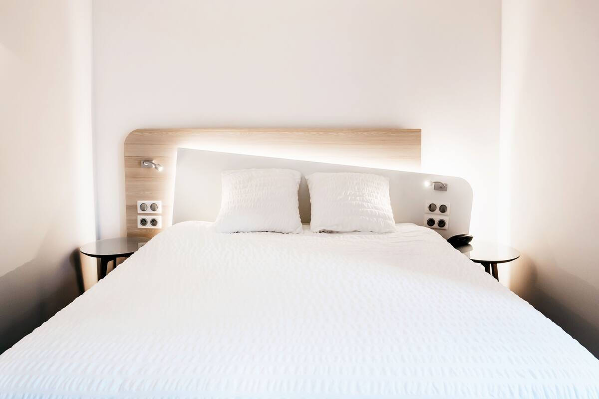 Ein modernes Hotelzimmer mit einem großen Bett, zwei Nachttischen und einem Holzkopfstück.