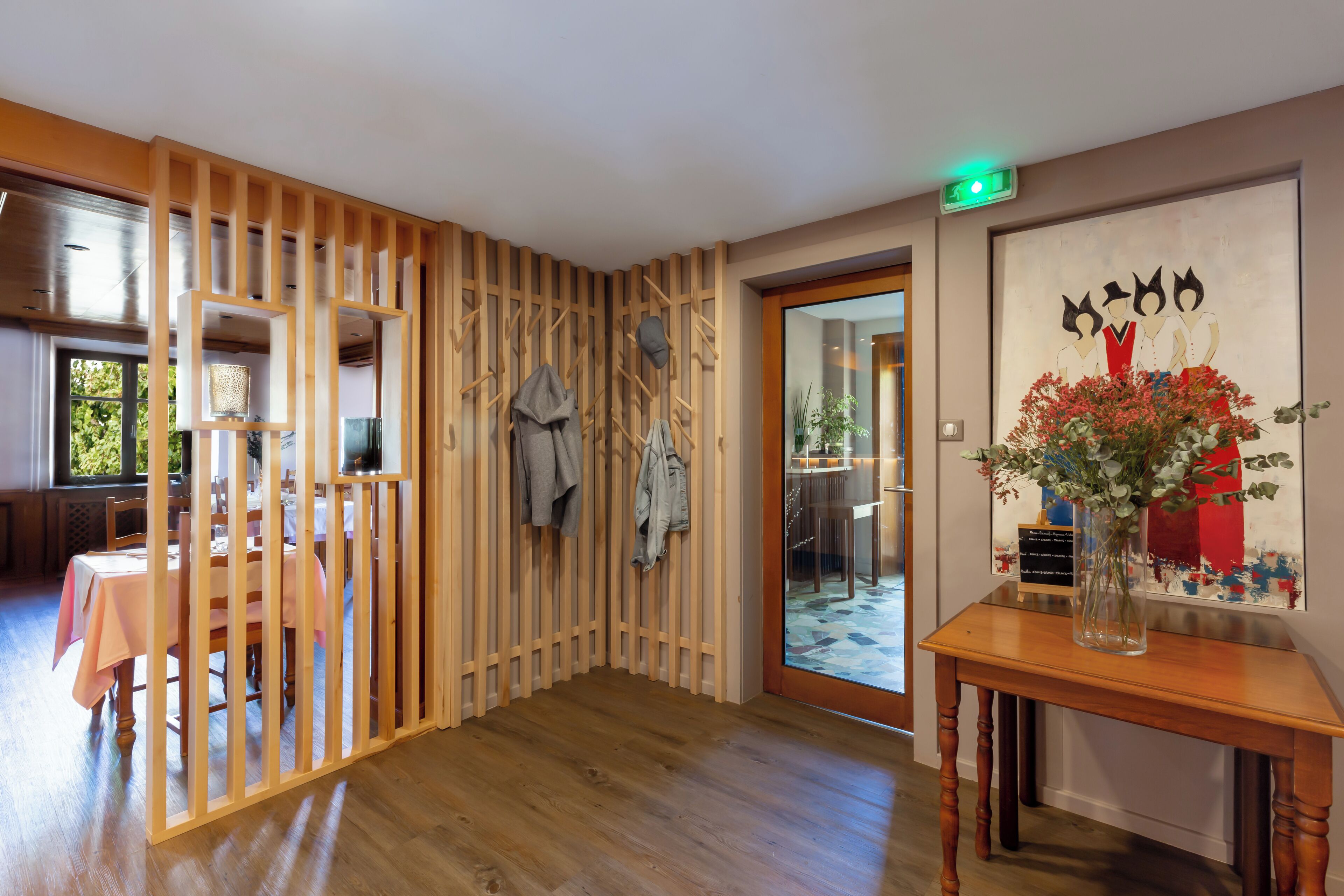 A room with a wooden partition, a table with a vase of flowers, and a door leading to another area.