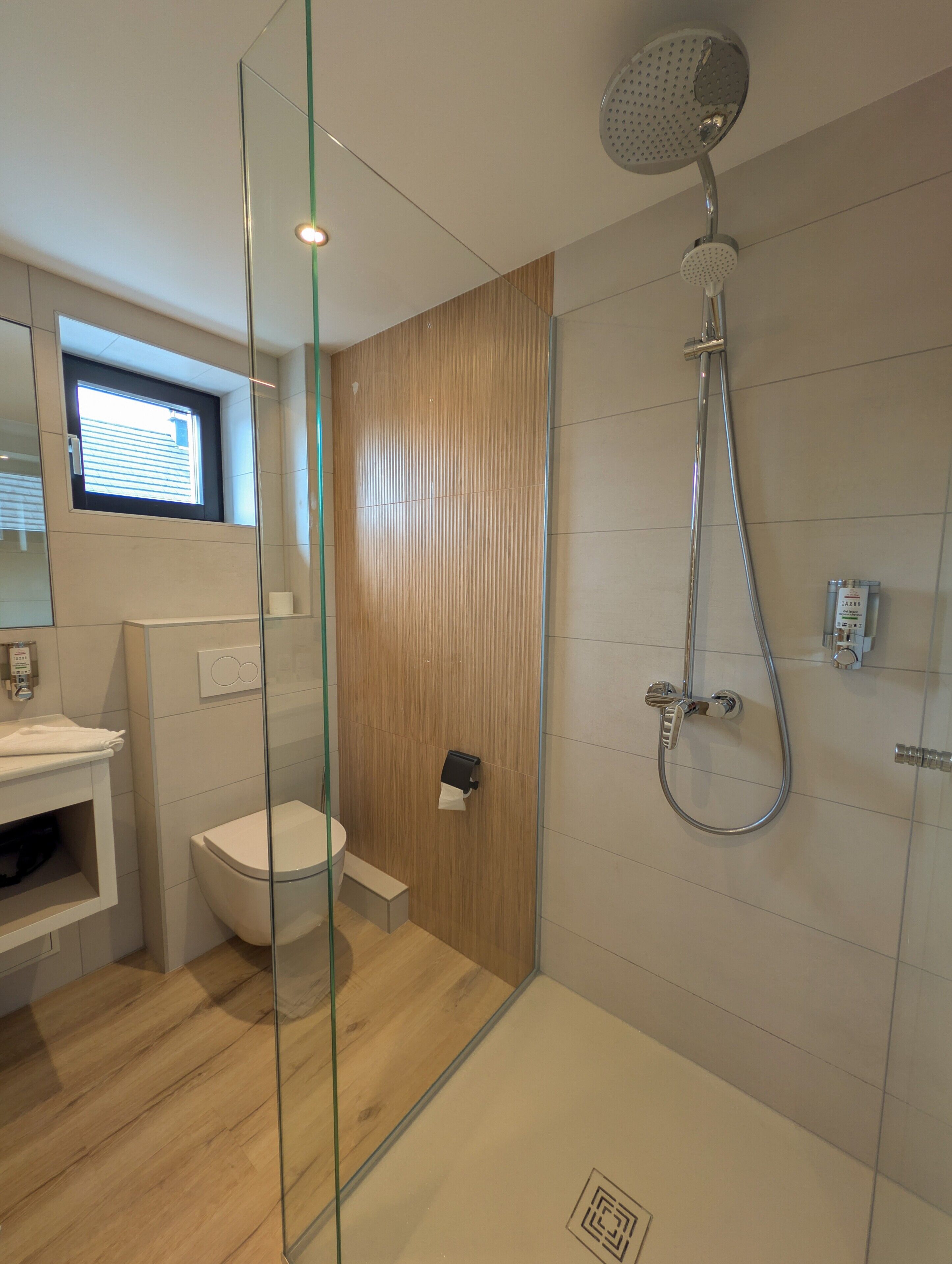 Un bagno moderno con box doccia in vetro, un water e un lavandino.
