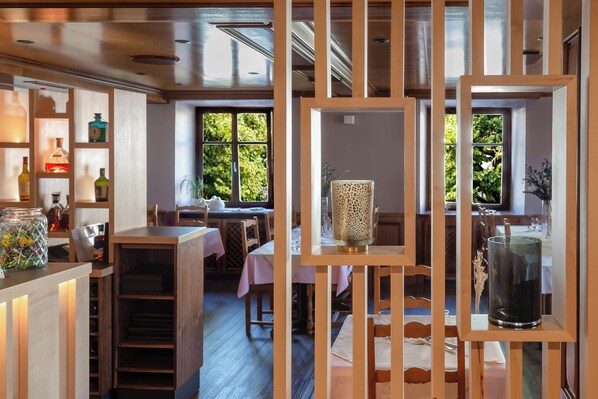 Un restaurante con mobiliario de madera, cristalería y vistas a zonas verdes.