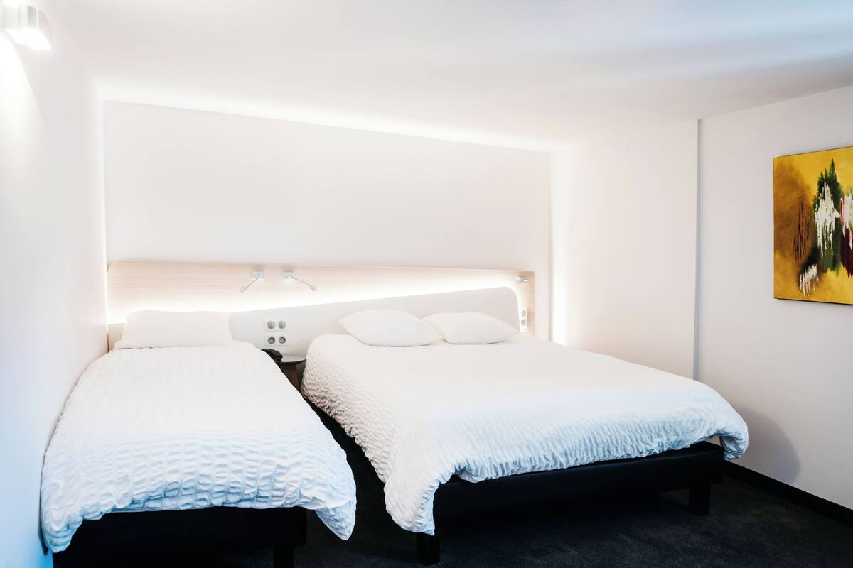 Ein modernes Hotelzimmer mit zwei Betten, einem großen Fenster und einem Gemälde an der Wand.