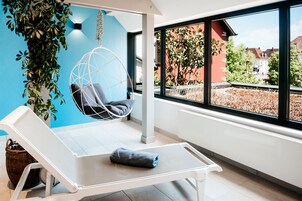 Una habitación moderna con una butaca blanca, una silla colgante y vistas a un jardín a través de amplios ventanales.