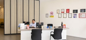 A reception desk with two monitors, a computer, and a printer. There are framed awards on the wall and a no-smoking sign.