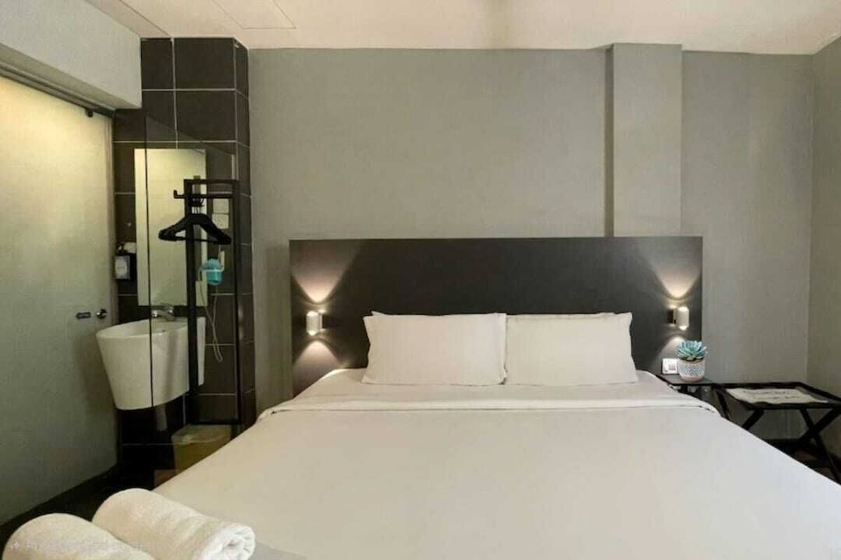 Una habitación de hotel con una cama grande, mesitas de noche, un espejo y un armario.