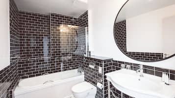 Un baño moderno con diseño de baldosas blanco y negro, una bañera, un inodoro y un lavamanos con un espejo grande.