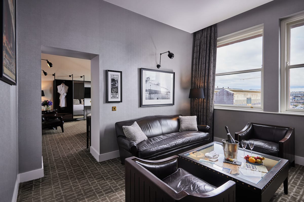 Habitación de hotel moderna con sofá de cuero, una mesa de centro de vidrio y vistas a la ciudad a través de amplios ventanales.