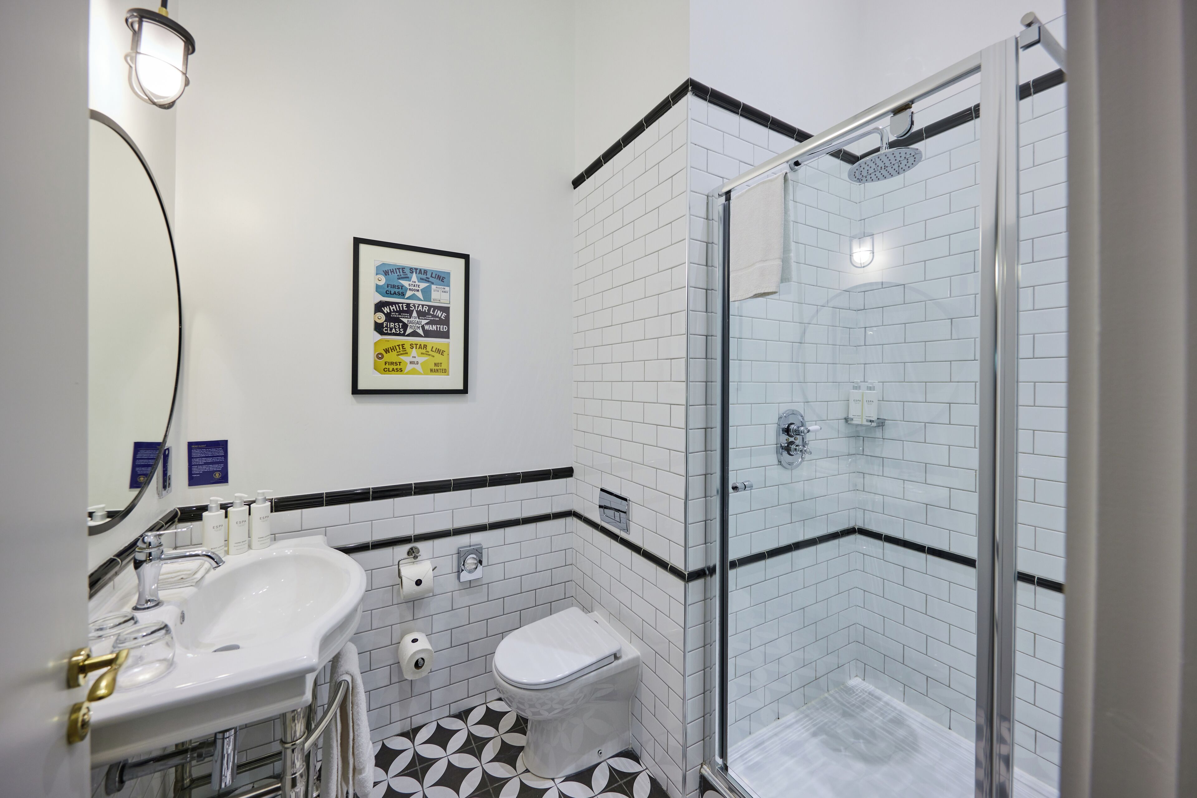 A modern bathroom with a glass-enclosed shower, a white sink with a gold faucet, and a toilet.