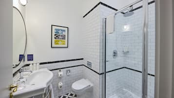 A modern bathroom with a glass-enclosed shower, a white sink with a gold faucet, and a toilet.