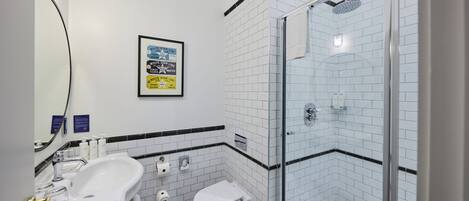 A modern bathroom with a glass-enclosed shower, a white sink with a gold faucet, and a toilet.