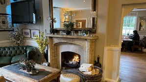 A cozy living room with a fireplace, green sofa, wooden coffee table, and a wicker basket. - Bedingfeld Arms (King's Lynn)