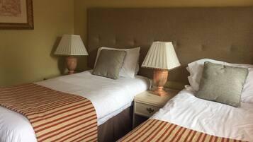 Una habitación de hotel con dos camas, cada una con colcha a rayas, dos lámparas de noche y una mesita de noche de madera.