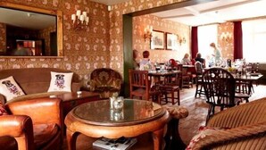 A cozy restaurant with a classic interior, featuring wooden furniture, floral wallpaper, and a dining area with patrons. - The Stag and Huntsman (Henley-on-Thames)