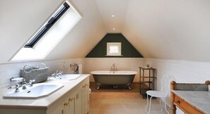 A modern bathroom with a skylight, a freestanding bathtub, and a vanity with a sink. - The Stag and Huntsman (Henley-on-Thames)