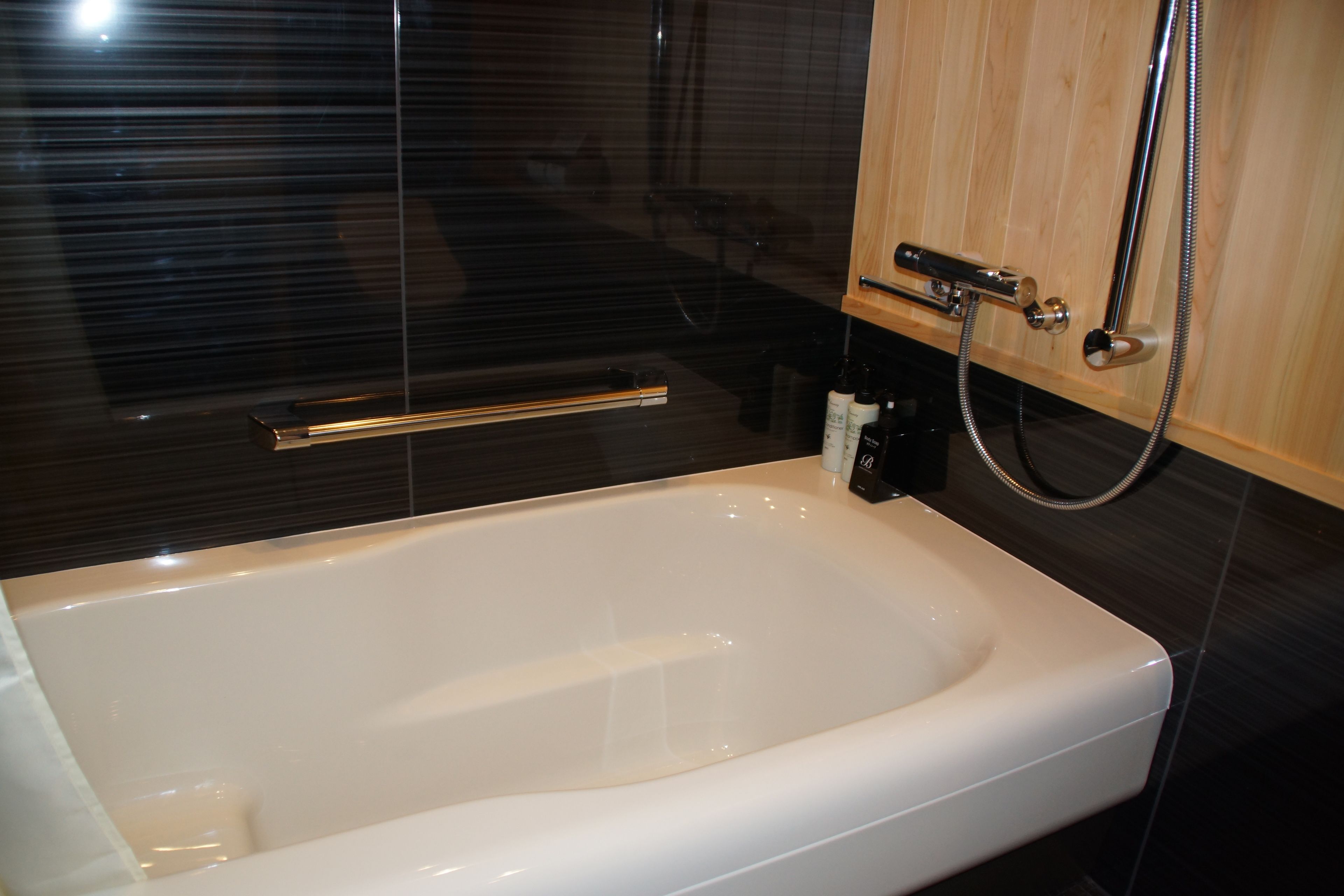 Un baño moderno con una bañera blanca, un mueble de madera y un box de ducha de cristal.