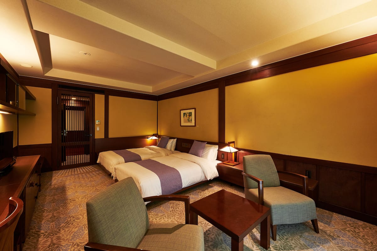 Una habitación de hotel con una cama grande, dos mesitas de noche, un escritorio y dos sillas.