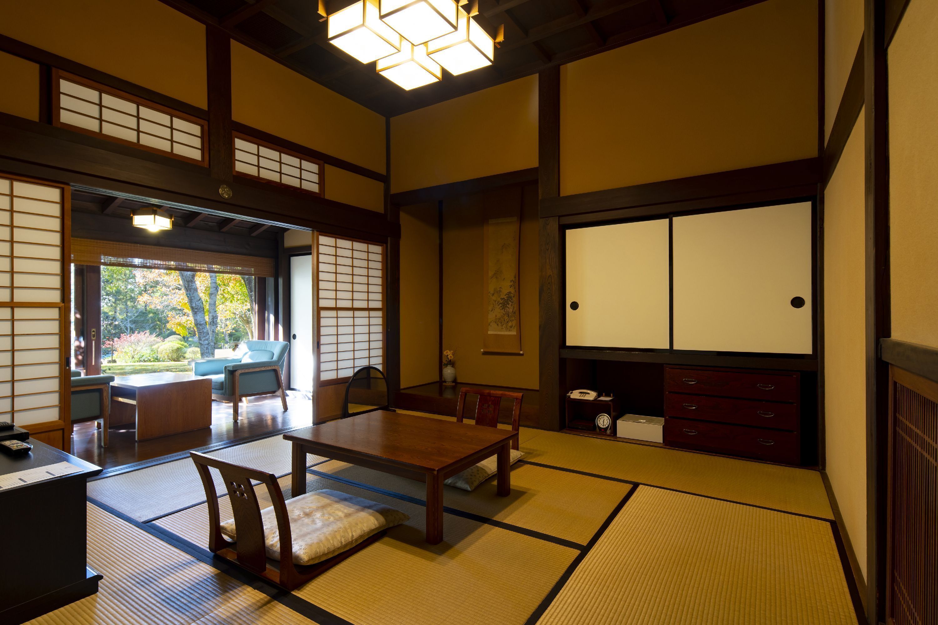 A traditional Japanese room with tatami flooring, a low table, and a sliding door leading to a garden.