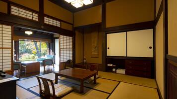 A traditional Japanese room with tatami flooring, a low table, and a sliding door leading to a garden.
